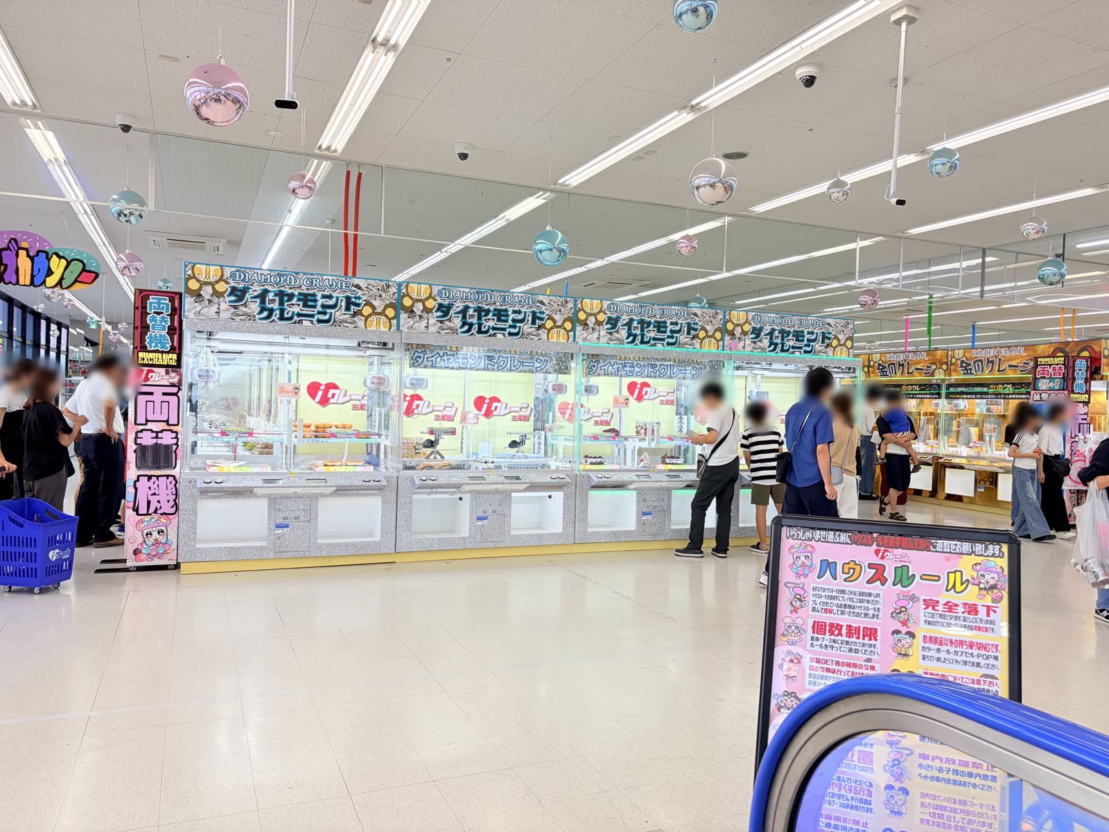 階段を上がってすぐのフロア。「ダイヤモンドクレーン」の看板を掲げた台が横一列に並び、右手前には「ハウスルール」の掲示板、左手に両替機が置かれている