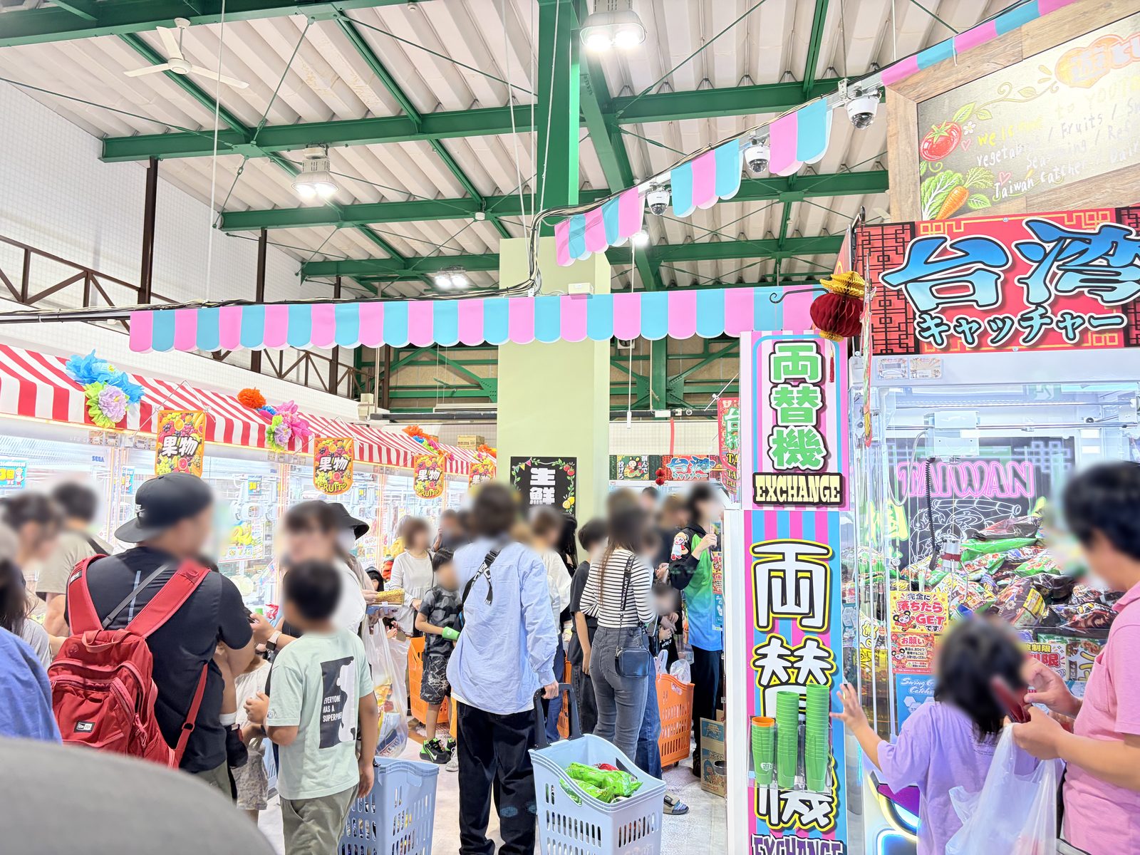 遊とぴあ新潟店の店内。右手に台湾キャッチャーの看板と両替機、左手から奥にかけて果物・生鮮コーナーの看板が並び、多くの来店客でにぎわっている