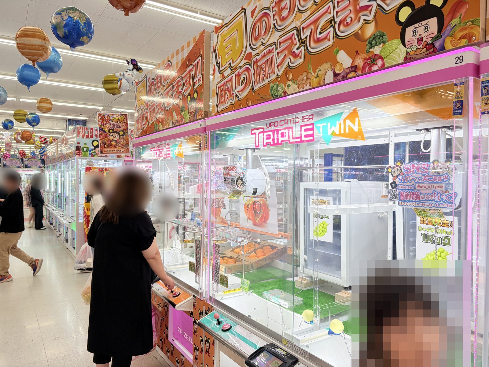 おたちゅう新潟本店の青果コーナー。UFOキャッチャー TRIPLE TWINの台に、シャインマスカット1パック・柿・みかんのポップが掲げられている