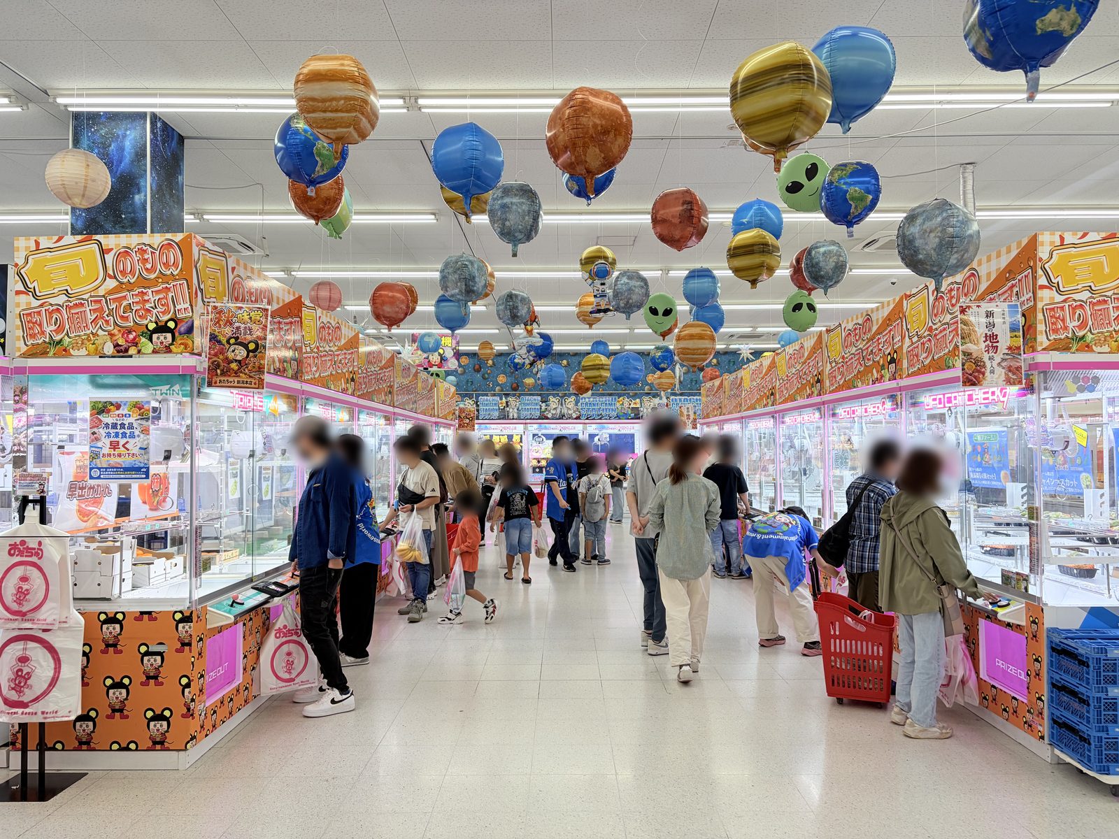 おたちゅう新潟本店の店内通路。両側の台の上に「旬のもの取り揃えてます」の看板が並び、天井には惑星のバルーンが吊るされている